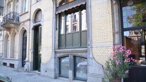 A building with a large window, a door, and a balcony.