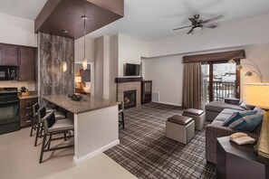 Enjoy a spacious living area with a seating area, kitchen, and fireplace, plus a balcony with a view.