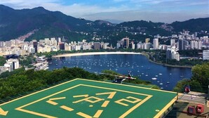 A sports court with a large logo, surrounded by a cityscape and a bay with boats. - Apartamento no Coração de Copacabana (Rio de Janeiro)