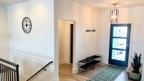 Ein modernes Interieur mit Treppe, einer Uhr, einer Tür und einer Pflanze.