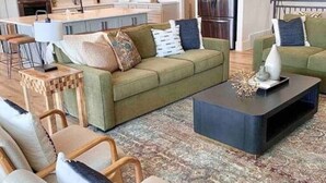 Ein modernes Wohnzimmer mit einem grünen Sofa, einem Couchtisch und einem gemusterten Teppich.
