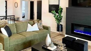 Ein modernes Wohnzimmer mit einem grünen Sofa, einem schwarzen Couchtisch und einem Kamin.