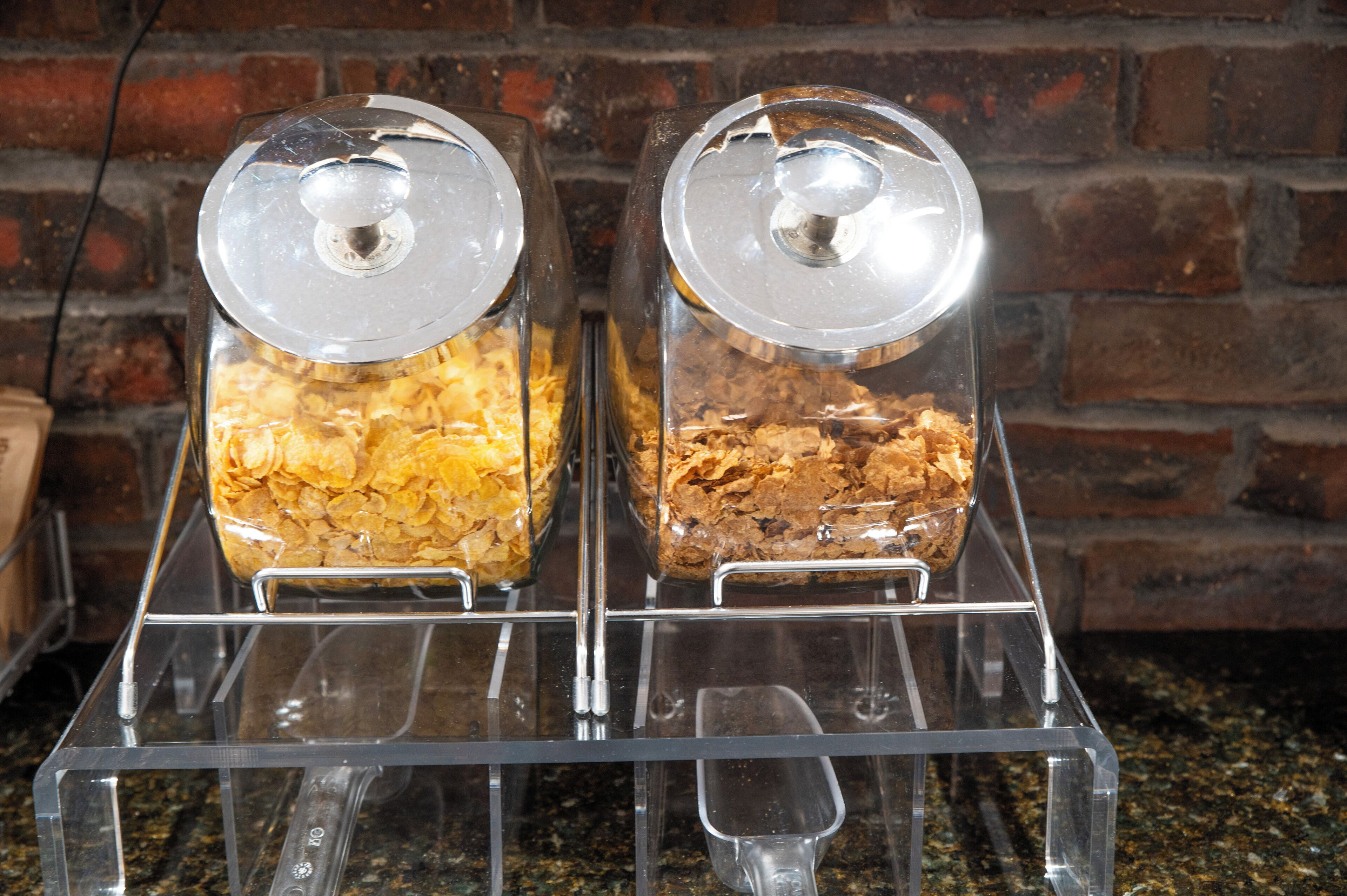 Two glass jars with lids on a clear metal rack against a brick wall.