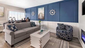 A living room with a sofa, coffee table, and patterned chair. There are two wall-mounted ship wheels and a framed picture on the wall. - Heritage House Inn on Cape Cod, an Ascend Collection Hotel (Hyannis)