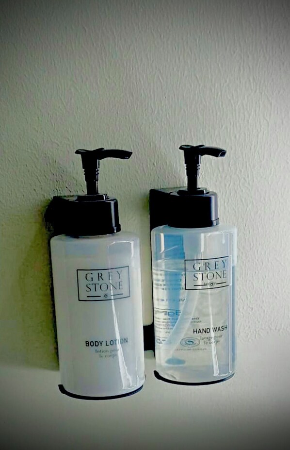 Dos botellas de loción corporal y jabón de manos Grey Stone.