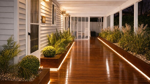 A covered walkway with wooden flooring, planter boxes with plants, and a white exterior wall. - Heritage House Inn on Cape Cod, an Ascend Collection Hotel (Hyannis)
