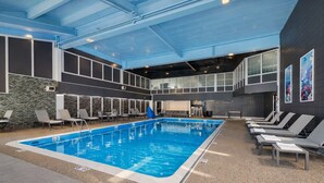 An indoor swimming pool with lounge chairs, a stone wall, and a mezzanine level. - Heritage House Inn on Cape Cod, an Ascend Collection Hotel (Hyannis)
