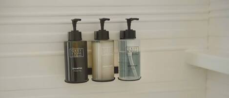 Three Grey Stone products on a wall: shampoo, conditioner, and body wash.