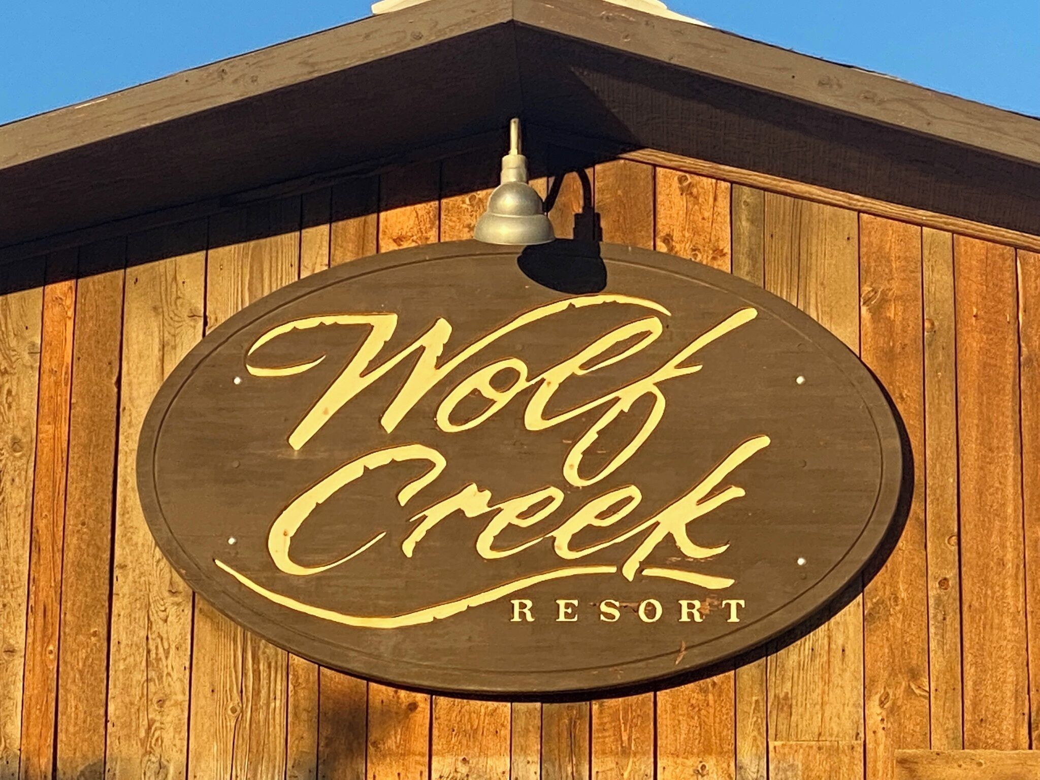 Une enseigne en bois portant l’inscription « Wolf Creek Resort » sur un fond en bois.
