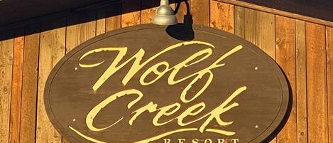 Une enseigne en bois portant l’inscription « Wolf Creek Resort » sur un fond en bois.