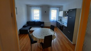 En kompakt opholdsstue med sofa, spisebord og tekøkken.