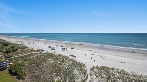 A beach with a wooden boardwalk, beach umbrellas, and a sandy shore. - Oceanfront Condo, Sanabel 505: 2BR 2BA with Outdoor Hot tub (North Myrtle Beach)