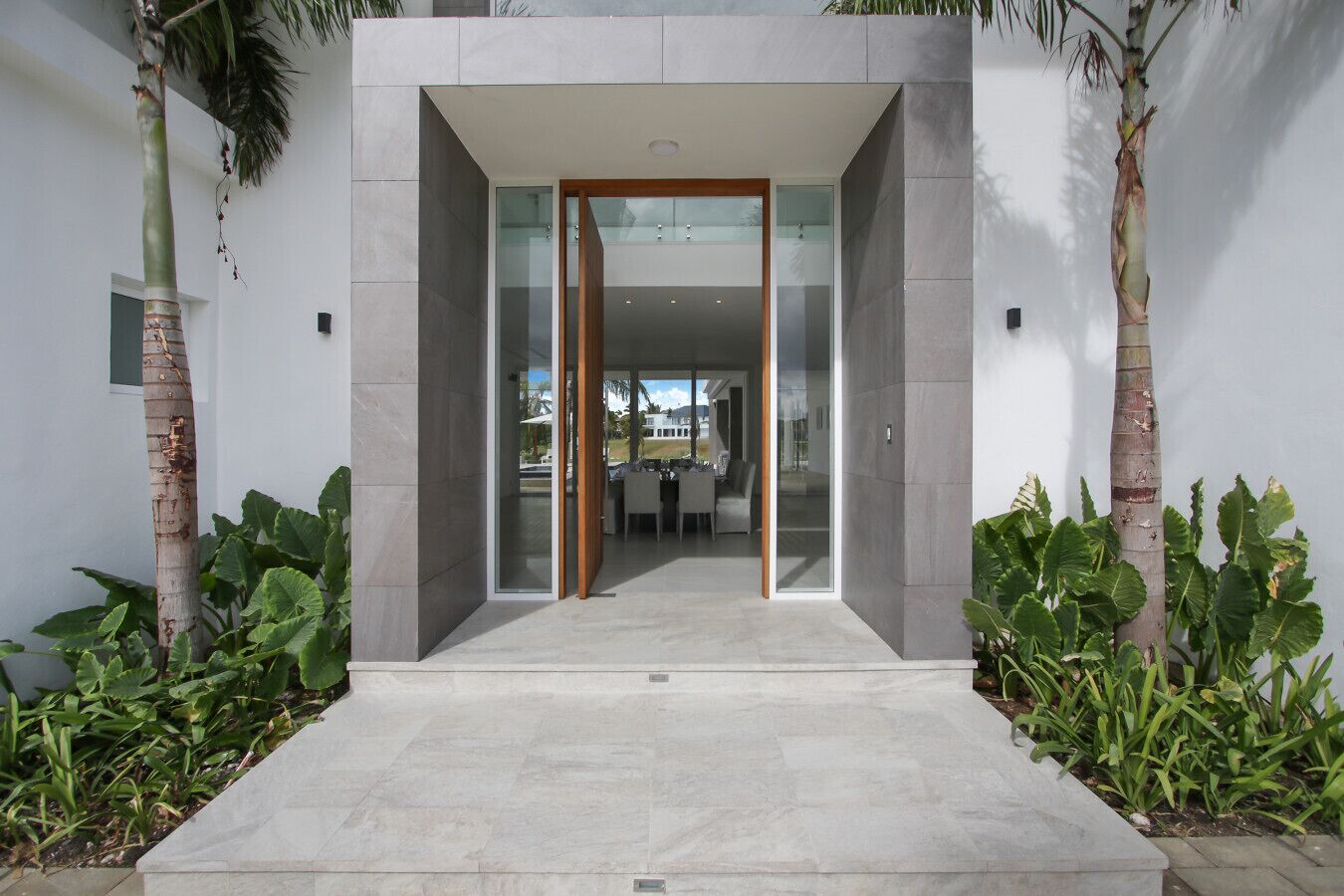 A modern entrance with a glass door leading to a dining area.