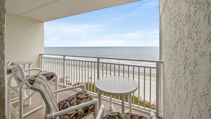 A balcony with a view of the beach, white metal chairs, and a small round table. - Sanabel 609: Oceanfront 2BR/2BA- Indoor Pool (North Myrtle Beach)