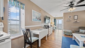 A spacious living area with a dining table, chairs, a sofa, and a ceiling fan.