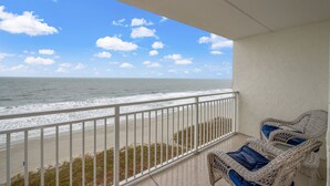 A balcony with wicker chairs and a view of the ocean.
