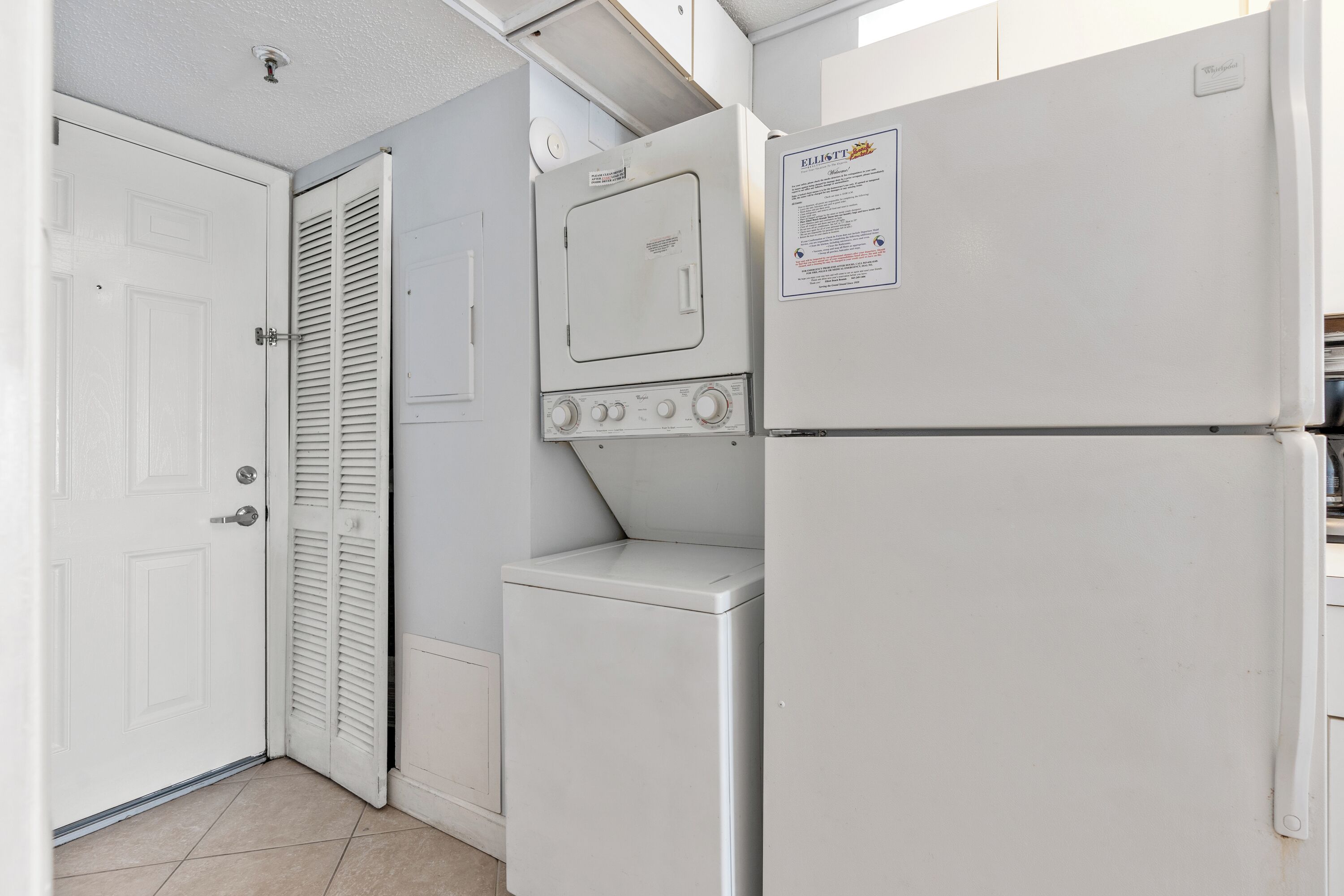 Uma lavanderia com máquina de lavar, secadora e uma porta.