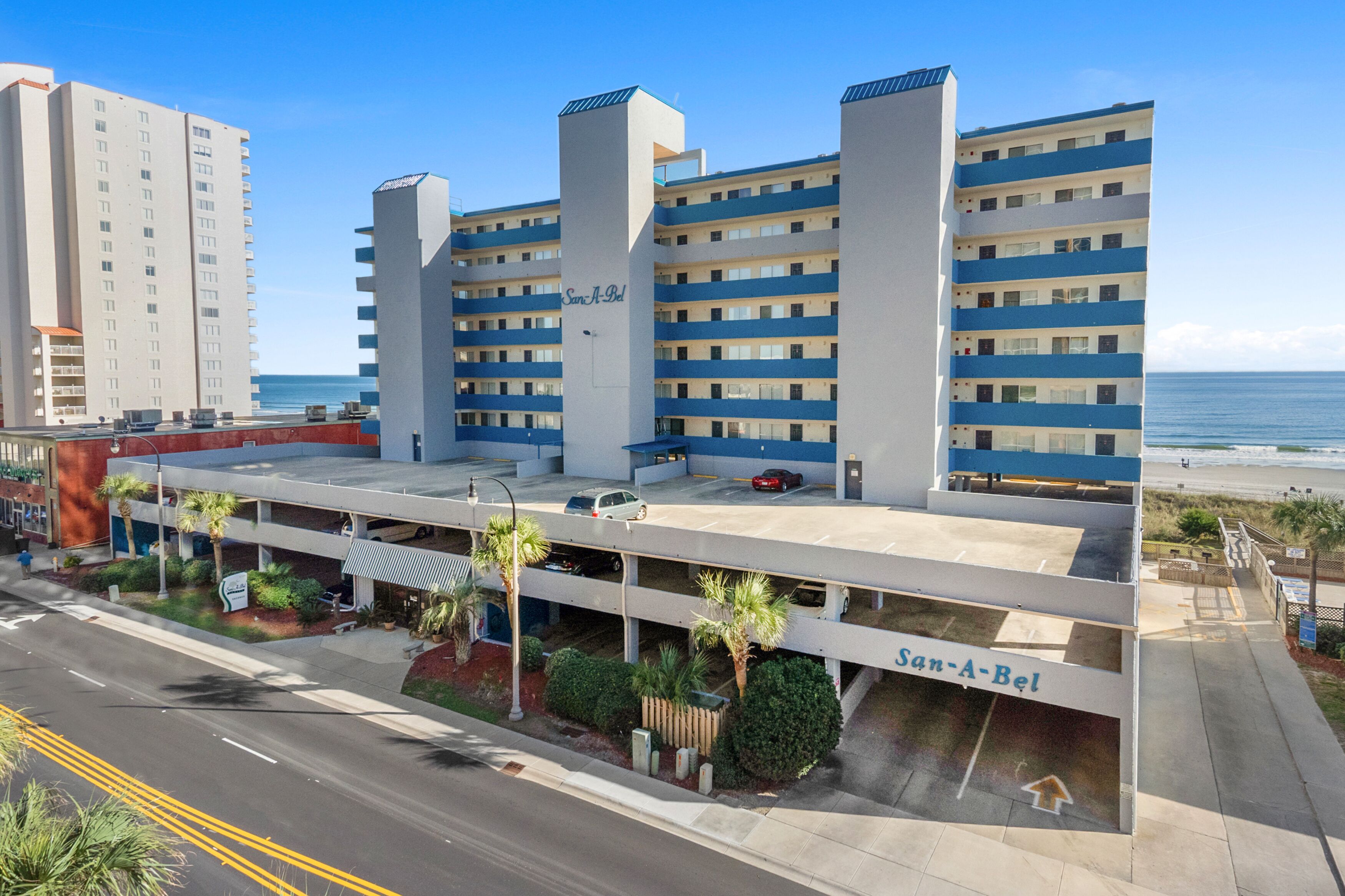 A multi-story parking structure with a sign reading "San-A-Bel" and a view of the ocean in the background.