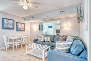 A living room with a sofa, coffee table, and a dining area with chairs.