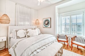 A bedroom with a large bed, two chairs, a bedside table, and a window with blinds. - Mykonos Sunset Villa South of 30-A, 4 Bikes, Sleeps 9, Steps to Gulf/Heated Pool (Rosemary Beach)