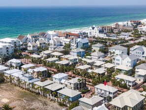 Zona residencial costera con casas de varios pisos, algunas con balcones, y una playa al fondo.