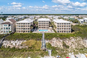 A resort with multiple buildings, a central pool, and a boardwalk leading to the beach. - Mykonos Sunset Villa South of 30-A, 4 Bikes, Sleeps 9, Steps to Gulf/Heated Pool (Rosemary Beach)