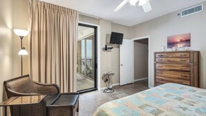 Een hotelkamer met een bed, een bureau, een stoel, een dressoir, een televisietoestel en een schuifdeur naar een balkon.