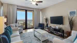 Een ruime woonkamer met balkon, een flatscreen televisie en een salontafel.