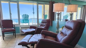 A room with a view of the beach, featuring two leather recliners, a table, and a lamp. - Let it BEach - Beach Property (Panama City Beach)