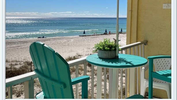 A balcony with a view of the beach, a round table with a potted plant, and two chairs. - Let it BEach - Beach Property (Panama City Beach)