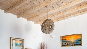 Un comedor con una mesa de madera, seis sillas, un ventilador y dos cuadros colgados en la pared.