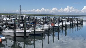 A marina with multiple boats docked at wooden piers, calm water, and a distant shoreline with grassy areas under a partly cloudy sky. - Brigantine Beach Gem!! Rated "Exceptional" by Guests.
Top of the Line (Brigantine)