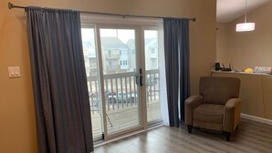 A room with a sliding glass door leading to a balcony, a brown armchair, and a ceiling light fixture. - Brigantine Beach Gem!! Rated "Exceptional" by Guests.
Top of the Line (Brigantine)
