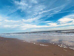 Une plage avec un ciel dégagé et des vagues sur l’océan.