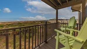 A balcony with a view of the beach and a building in the background.