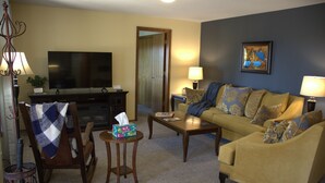 A living room with a sofa, armchair, coffee table, television, and lamps. - Hayden Lake Retreat • Lake Views • Private Deck • Near Coeur d'Alene (Coeur d'Alene)
