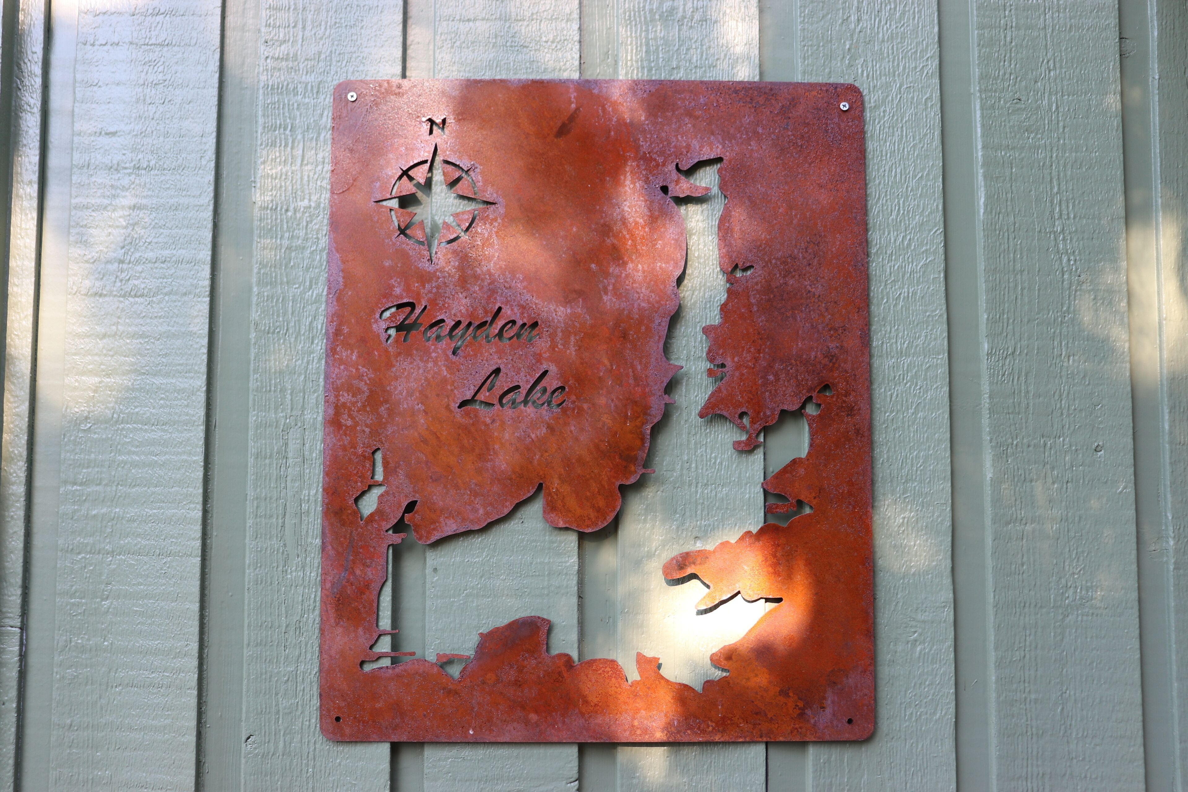 Een metalen bord met een kaartontwerp en de tekst ‘Hayden Lake’.