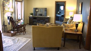 A living room with a sofa, armchair, and a television. - Hayden Lake Retreat • Lake Views • Private Deck • Near Coeur d'Alene (Coeur d'Alene)