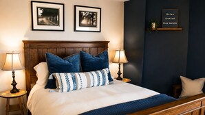 A neatly made bed with a wooden headboard, two bedside lamps, and a framed sign on the wall. - Hayden Lake Retreat • Lake Views • Private Deck • Near Coeur d'Alene (Coeur d'Alene)