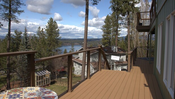 A wooden deck with a table and a view of a lake and mountains. - Hayden Lake Retreat • Lake Views • Private Deck • Near Coeur d'Alene (Coeur d'Alene)