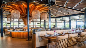 A spacious restaurant with a high ceiling, large windows, and a central seating area with a bar.