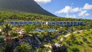 A resort with multiple-story buildings, a swimming pool, and lush greenery.