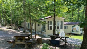 Un terrain de camping équipé de tables de pique-nique, d'un mobil-home et d'une zone délimitée par une clôture.