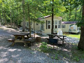 Un camping con mesas de picnic, una casa rodante y un área cercada.