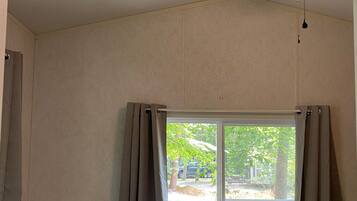 Un dormitorio con una cama individual, un ventilador de techo, una ventana con cortinas y una señal de salida.