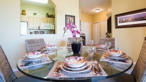 A dining area with a glass table set for six, surrounded by wicker chairs. - Magical Location Condo Close to Clubhouse & Pool - Windsor Hill Resort (Kissimmee)