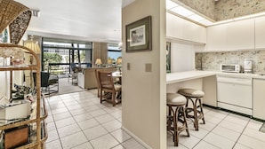 A modern kitchen with white cabinets, a dining area with a table and chairs, and a large window providing natural light.