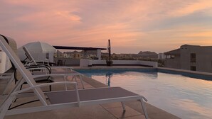 A rooftop pool area with lounge chairs and umbrellas, surrounded by buildings and a clear sky. - Amazing penthouse close to the beach (Cabo San Lucas)