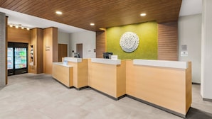 A reception area with wooden reception desks, a green accent wall, and a circular decorative piece. - Fairfield Inn & Suites by Marriott Seattle Downtown/Seattle Center (Seattle)