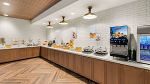 A modern kitchen with wooden cabinets, a herringbone floor, and a juice dispenser. - Fairfield Inn & Suites by Marriott Seattle Downtown/Seattle Center (Seattle)